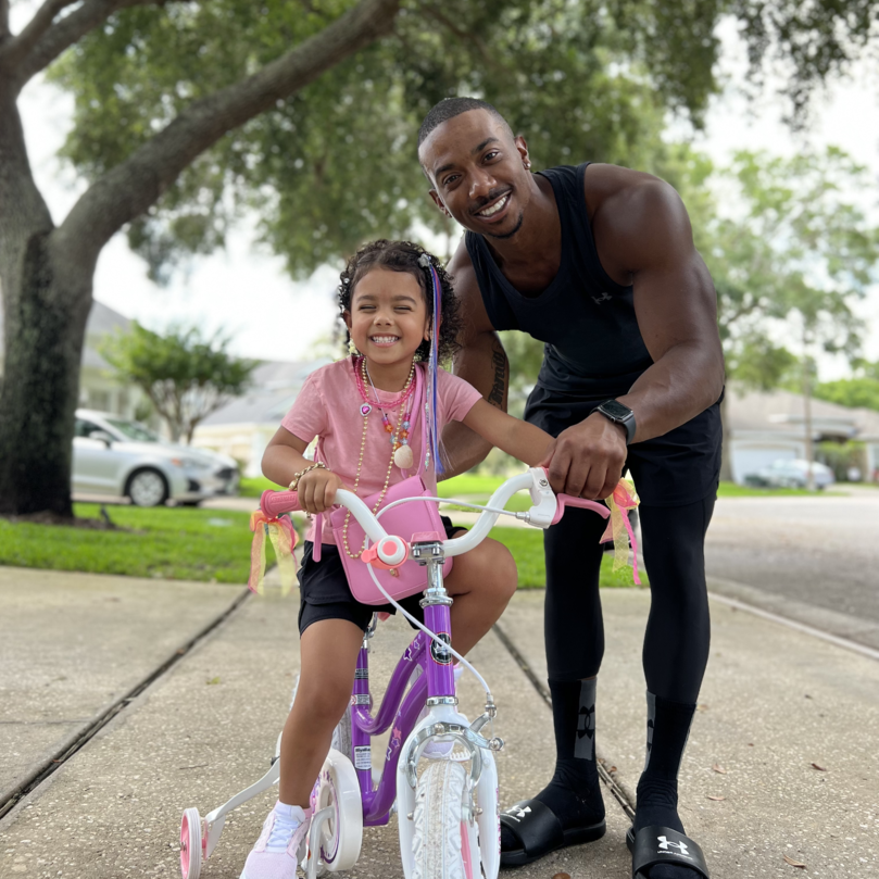 father teaching daughter to ride a bike